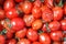 Closeup plenty crumpled red fresh ripe cherry tomatoes together with stems are awaiting distribution in box on farmers market.