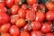 Closeup plenty crumpled red fresh ripe cherry tomatoes together with stems are awaiting distribution in box on farmers market.