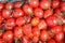 Closeup plenty crumpled red fresh ripe cherry tomatoes together with stems are awaiting distribution in box on farmers market.