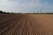 Closeup of a plowed field, trees and greenery on the background