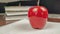 Closeup of pomodoro study technique kitchen timer in shape of a red apple for timing the studying with notebook and books in