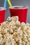 Closeup popcorn on the background of red plastic cups with fizzy drink.