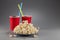 Closeup popcorn on the background of red plastic cups with fizzy drink with colored straws