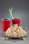 Closeup popcorn on the background of red plastic cups with fizzy drink with colored straws