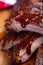 Closeup of pork ribs grilled with caramelized BBQ sauce. Tasty snack on a wooden Board