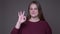 Closeup portarit of young overweight caucasian female gesturing ok handsign looking at camera with background isolated