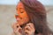 Closeup portrait of adorable brunette woman celebrating Holi colors festival at the desert