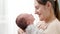 Closeup portrait of adorable little baby and smiling mother looking at each other against big window at house. Concept