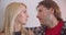 Closeup portrait of adult affectionate caucasian couple looking tenderly at each other and sitting on sofa indoors in