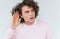 Closeup portrait of amazed eavesdropping male with curly hair placing hand on ear asking someone to speak up, isolated over white