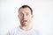 Closeup portrait of astonished surprised 30 years old caucasian white man on white background in white t-shirt with stubble on