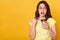 Closeup portrait of astonished woman posing against yellow studio background, looks surprised, being shocked, holding takeaway