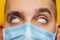 Closeup portrait of an attractive young man rolled his eyes in a protective mask on his face. Fear of getting sick, coronavirus