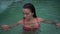 Closeup portrait of beautiful brunette woman wearing pink bikini relaxing in outdoor swimming pool at tropical resort.