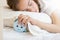 Closeup portrait of beautiful teenage girl sleeping and holding hand on alarm clock