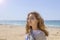Closeup portrait of a beautiful young Caucasian fashion model posing on the seashore in sunny weather, looking into the distance,