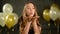 Closeup Portrait of Birthday Girl with Handful of Golden Confetti. Smiling Young Woman is Blowing on Her Hands Enjoying