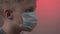 A closeup portrait of a blonde caucasian child putting on a surgical mask as a prevention measure against being infected