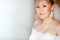 Closeup portrait of bride in lace white wedding dress with elegant earrings, copy space.