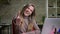 Closeup portrait of caucasian female office worker in front of the laptop smiling pulling her arm and showing thumb up