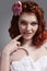 Closeup Portrait of Caucasian Redhaired Girl in White Bridal Dress Posing Against gray, holding Point Finger Near Mouth