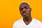 Closeup portrait of a charming honest handsome black blond African man on an orange background