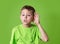Closeup portrait child hearing something, parents talk, gossips, hand to ear gesture isolated on green background.