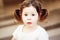 Closeup portrait of cute adorable sad upset white Caucasian toddler girl child with dark brown eyes and curly pig-tails