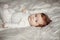 Closeup portrait of cute Caucasian newborn baby. Adorable funny child infant with blue grey eyes and red hair lying on a bed