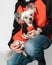 Closeup portrait of cute Chinese Crested dog sitting on owner arms and looking into camera. Both wear the same oramge