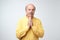 Closeup portrait of desperate mature man in yellow shirt showing clasped hands,asking for help or excuse.