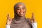 Closeup portrait of dreamy black muslim girl in headscarf crossing fingers