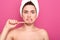 Closeup portrait of emotional unsatisfied woman with white towel on her head, brushing her teeth with professional equipment,