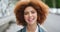 Closeup portrait of the face of a beautiful young woman with an afro traveling solo in the urban city. Edgy female with
