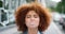 Closeup portrait of the face and head of a beautiful young woman with an afro, chewing gum and blowing bubbles. Edgy and
