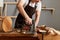 Closeup portrait of faceless craftsman wearing white t-shirt and brown apron working, joinery work, wood carving, chisels for