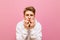 Closeup portrait of a frightened young man on a pink background, with shocked face looks into the camera. Funky guy in white