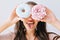 Closeup portrait funny girl with long hair having fun with colorful donuts against her eyes. Attractive young woman with