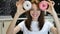 Closeup portrait of funny girl with long hair having fun with colorful donuts against her eyes at the kitchen at home