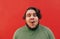 Closeup portrait of a funny satisfied young hispanic guy on a red background, feeling excited and amazed, looking at the camera