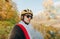Closeup portrait of handsome cyclist man in sunglasses and helmet on background of beautiful autumn park landscape, looking into