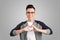 Closeup portrait handsome smiling young business man makes the heart using fingers, hands, isolated grey wall background. Positive