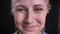 Closeup portrait of happy middle-aged caucasian female face looking straight at camera and smiling kindly