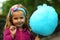 Closeup portrait of happy toddler girl eating blue cotton candy