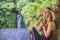 Closeup portrait image of a beautiful woman drinking ice tea with feeling happy in green nature and waterfall garden