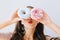 Closeup portrait joyful girl with red lips having fun with colorful donuts against her eyes. Attractive young woman with