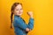 Closeup portrait of a little girl on a yellow background. Children`s hand shows biceps. Girl power concept