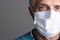 Closeup portrait of a mature male doctor wearing a surgical mask. Only partial face is seen with copy space on a gray background