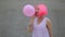 Closeup portrait of mixed race trendy hipster teenage girl blowing a red balloon wearing pink wig