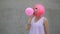 Closeup portrait of mixed race trendy hipster teenage girl blowing a red balloon wearing pink wig